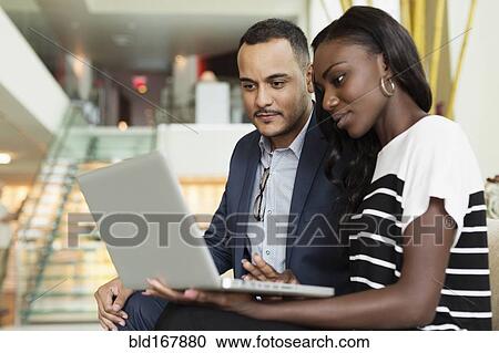 Business people using laptop in hotel lobby View Large Photo Image Stock Image - Business people using laptop in hotel lobby. Fotosearch