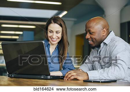 Picture - Business people using laptop in office. Fotosearch