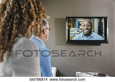 Picture - Business people watching teleconference in office meeting. Fotosearch