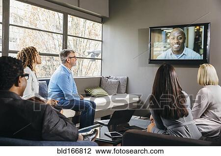Business people watching teleconference in office meeting View Large Photo Image Stock Image - Business people watching teleconference in office meeting. Fotosearch