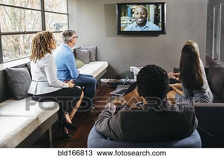 Stock Image - Business people watching teleconference in office meeting. Fotosearch
