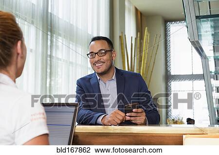 Businessman checking into hotel with concierge View Large Photo Image Stock Image - Businessman checking into hotel with concierge. Fotosearch