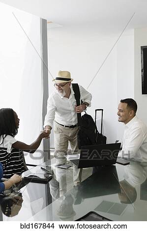 Businessman greeting colleagues in office meeting View Large Photo Image Picture - Businessman greeting colleagues in office meeting. Fotosearch