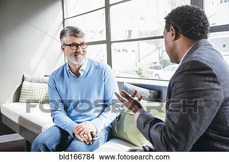 Picture - Businessmen talking in office lobby. Fotosearch
