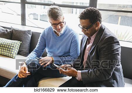Businessmen using cell phone in office View Large Photo Image Stock Photo - Businessmen using cell phone in office. Fotosearch