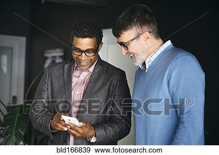 Stock Photo - Businessmen using cell phone in office. Fotosearch