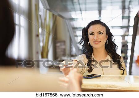 Stock Photograph - Businesswoman checking into hotel with concierge. Fotosearch