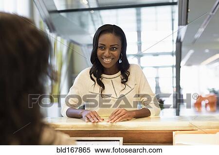 Stock Photography - Businesswoman checking into hotel with concierge. Fotosearch