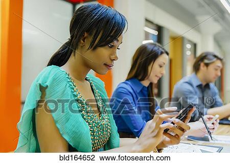 Businesswoman using cell phone in office meeting View Large Photo Image Stock Image - Businesswoman using cell phone in office meeting. Fotosearch