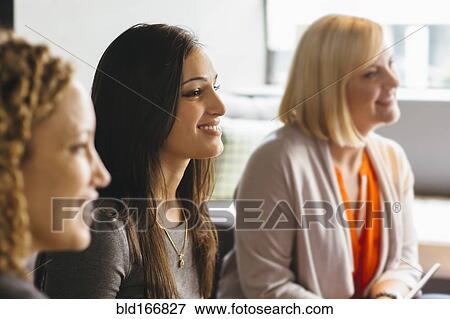 Stock Photo - Businesswomen listening in office meeting. Fotosearch