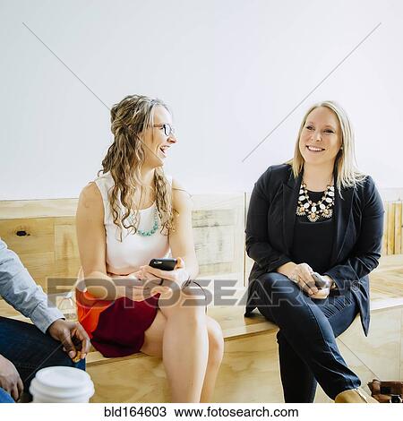 Stock Image - Businesswomen talking in office lobby. Fotosearch