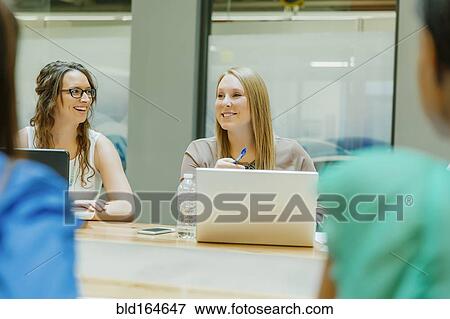 Stock Photo - Businesswomen talking in office meeting. Fotosearch