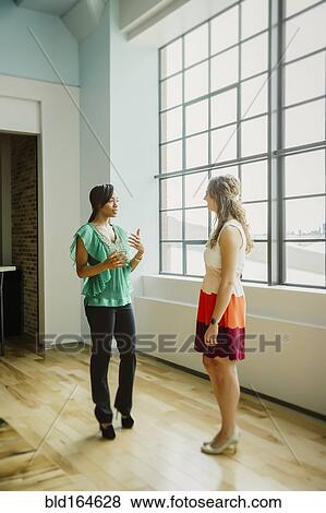 Stock Photo - Businesswomen talking in office. Fotosearch