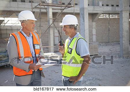 Caucasian architect and construction worker talking at construction site View Large Photo Image Stock Photo - Caucasian architect and construction worker talking at construction site. Fotosearch