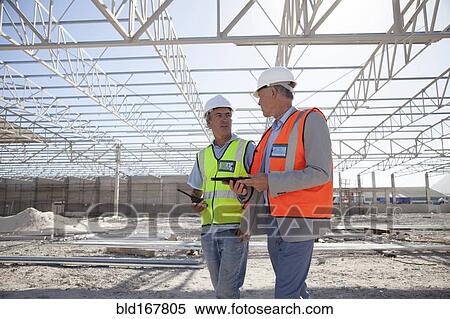 Stock Photography - Caucasian architects talking at construction site. Fotosearch