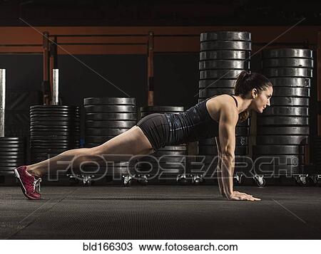Stock Image - Caucasian athlete doing push-ups in gym. Fotosearch