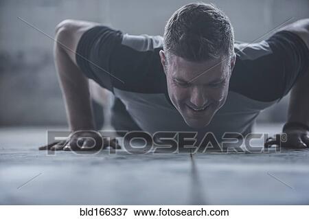 Stock Photo - Caucasian athlete doing push-ups on floor. Fotosearch