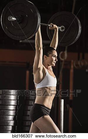 Stock Photo - Caucasian athlete lifting weights in gym. Fotosearch