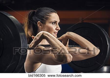 Stock Photography - Caucasian athlete lifting weights in gym. Fotosearch