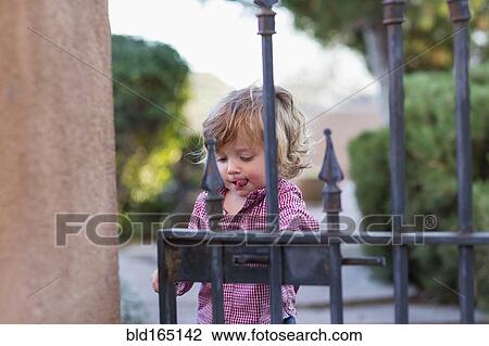 Stock Image - Caucasian baby boy playing at gate. Fotosearch