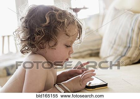 Caucasian baby boy playing with cell phone on sofa View Large Photo Image Stock Photography - Caucasian baby boy playing with cell phone on sofa. Fotosearch