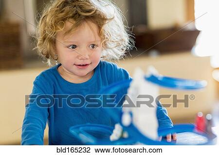 Stock Image - Caucasian baby boy playing with toy in living room. Fotosearch