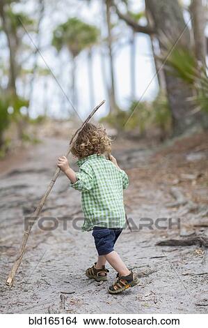 Picture - Caucasian baby boy walking on dirt path. Fotosearch