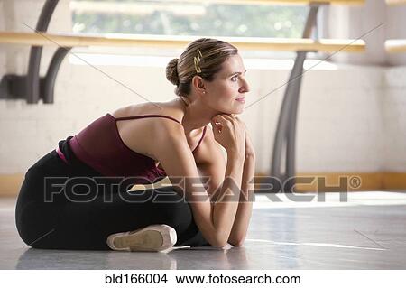 Picture - Caucasian ballet dancer sitting on floor in studio. Fotosearch