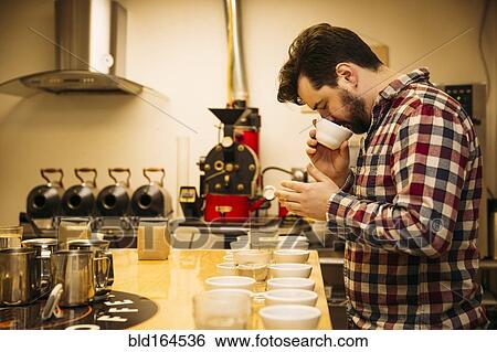 Stock Photograph - Caucasian barista tasting coffee in coffee shop. Fotosearch