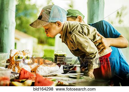 Stock Photo - Caucasian boy blowing out candles on birthday cake. Fotosearch
