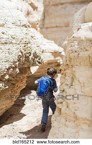 Stock Image - Caucasian boy exploring desert rock formations. Fotosearch