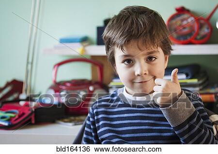 Caucasian boy giving thumbs up at desk View Large Photo Image Stock Photograph - Caucasian boy giving thumbs up at desk. Fotosearch
