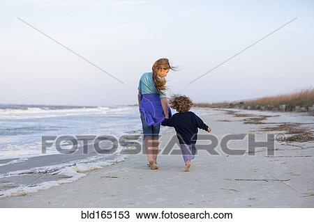 Stock Image - Caucasian brother and sister walking on beach. Fotosearch