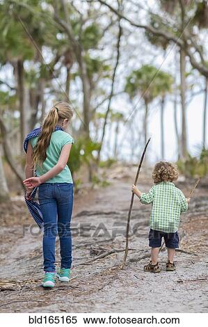 Stock Photography - Caucasian brother and sister walking on dirt path. Fotosearch