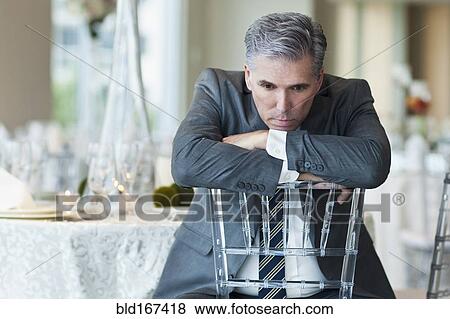 Stock Photo - Caucasian businessman brooding in empty dining room. Fotosearch