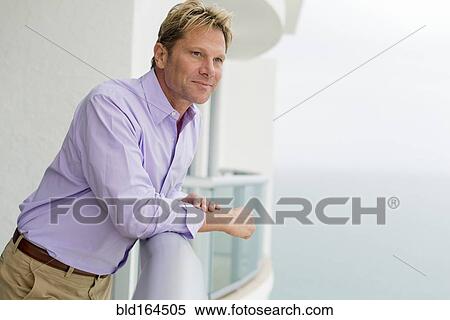 Caucasian businessman leaning on balcony View Large Photo Image Stock Photography - Caucasian businessman leaning on balcony. Fotosearch