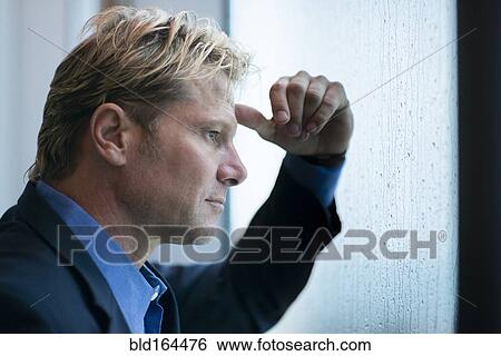 Stock Photograph - Caucasian businessman standing at rainy office window. Fotosearch