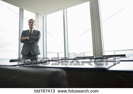 Stock Image - Caucasian businessman standing in empty conference room. Fotosearch