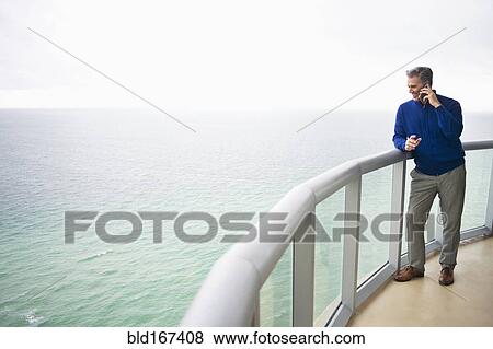Caucasian businessman talking on cell phone on balcony View Large Photo Image Stock Photo - Caucasian businessman talking on cell phone on balcony. Fotosearch