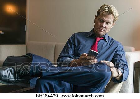 Caucasian businessman using cell phone in office lobby View Large Photo Image Stock Photo - Caucasian businessman using cell phone in office lobby. Fotosearch