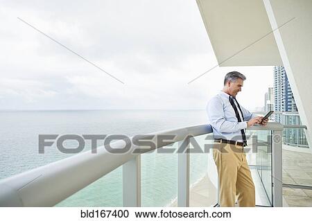 Stock Image - Caucasian businessman using digital tablet on balcony. Fotosearch