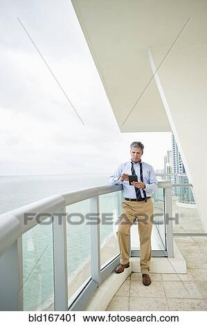 Caucasian businessman using digital tablet on balcony View Large Photo Image Stock Image - Caucasian businessman using digital tablet on balcony. Fotosearch