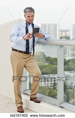Caucasian businessman using digital tablet on balcony View Large Photo Image Stock Image - Caucasian businessman using digital tablet on balcony. Fotosearch