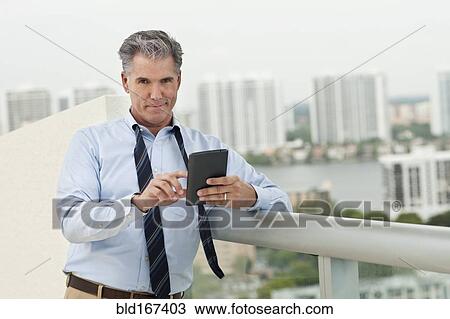 Stock Image - Caucasian businessman using digital tablet on balcony. Fotosearch