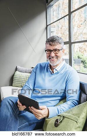 Stock Photo - Caucasian businessman using digital tablet in office lobby. Fotosearch
