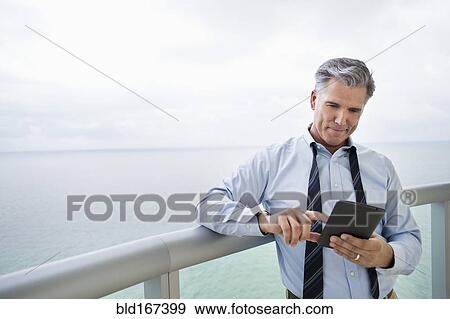 Caucasian businessman using digital tablet on balcony View Large Photo Image Stock Photo - Caucasian businessman using digital tablet on balcony. Fotosearch