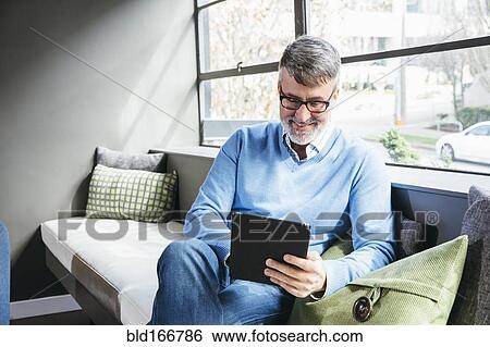 Stock Photograph - Caucasian businessman using digital tablet in office lobby. Fotosearch