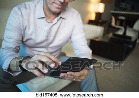 Stock Photography - Caucasian businessman using digital tablet in hotel room. Fotosearch
