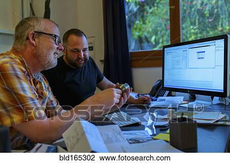 Stock Image - Caucasian businessmen working at desk. Fotosearch