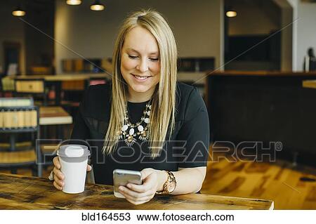 Stock Image - Caucasian businesswoman using cell phone in cafe. Fotosearch